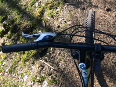 Kierownica roweru górskiego od góry na ścieżce rowerowej w puszczy kampinoskiej